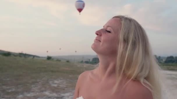 Jovem mulher loira bonita em um vestido branco girando na montanha. Modelo de moda atraente com cabelo voador. Mulher bonita sacode o cabelo. Movimento lento — Vídeo de Stock