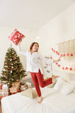Tatiller, yeni yıl, dekorasyon ve kutlama konsepti - yatağında hediyeler olan büyük bir Noel ağacı. Yeni yıl iç mimarisi. Odadaki kadın