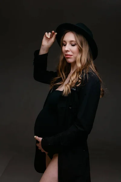 Een zwangere vrouw in een zwart pak en een zwarte hoed. Ruimte om te kopiëren. Het concept van gezonde spijsvertering, levensstijl, IVF — Stockfoto