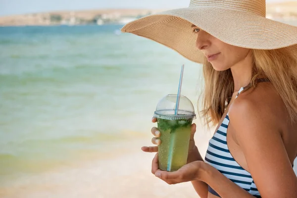 Δίαιτα. Υγιεινή διατροφή και ξεκούραση. γυναίκα πίνει κοκτέιλ σε γυάλινο φόντο θάλασσα. Μια γυναίκα στην παραλία απολαμβάνει τη ζωή. — Φωτογραφία Αρχείου