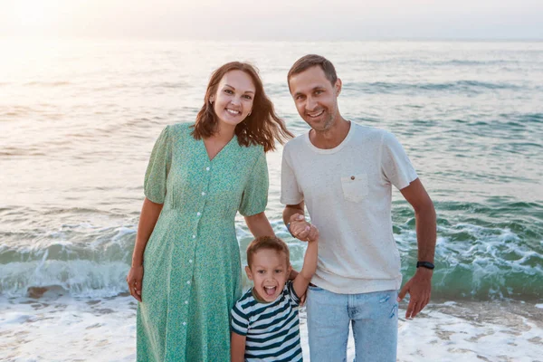 Dovolená na moři. Po pláži se prochází rodina. rodina drží za ruce — Stock fotografie