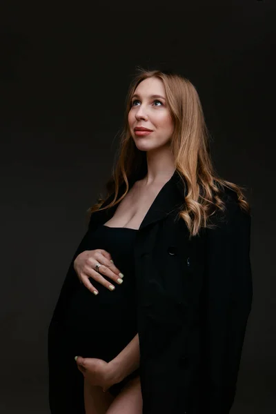 Una mujer embarazada con traje negro y sombrero negro. Espacio para copiar. El concepto de digestión saludable, estilo de vida, FIV —  Fotos de Stock