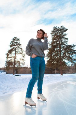 Buz üstünde artistik patinajcı. Kız kayıyor. Açık gökyüzünün altındaki buz. Kışın makyaj yok, kırmızı yanak.