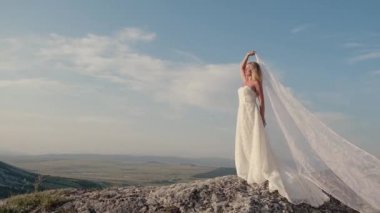 Dağda dönen beyaz elbiseli güzel sarışın kadın. Uçan saçlı çekici bir manken. Güzel kız saçlarını sallıyor. Yavaş çekim