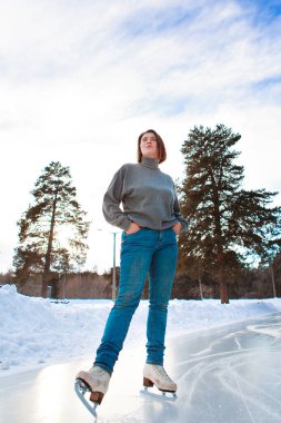 Buz üstünde artistik patinajcı. Kız kayıyor. Açık gökyüzünün altındaki buz. Kışın makyaj yok, kırmızı yanak.