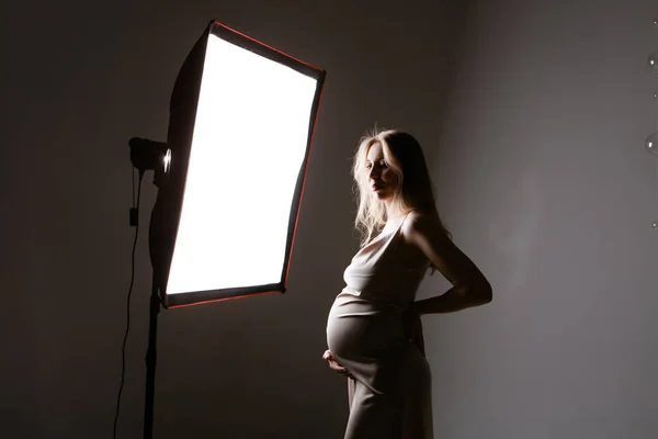 Una Mujer Embarazada Con Traje Negro Acaricia Vientre Sobre Fondo — Foto de Stock