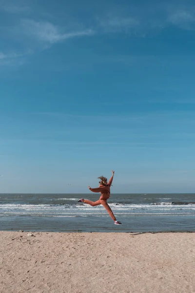 Nő ugrás boldog a strandon egy kék ég és a tenger a háttérben — Stock Fotó