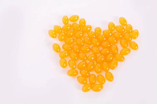 Vitamina D e Omega 3 cápsulas de óleo de peixe suplemento em uma placa em forma de coração sobre fundo branco. Conceito de saúde, Dia dos Namorados. — Fotografia de Stock