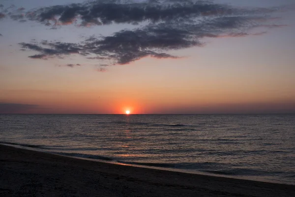 Beautiful sunset over sea with reflection in water, majestic clouds in the sky Stock Photo