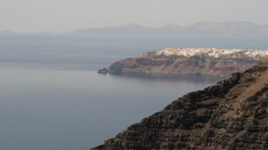 Uzaktan tepenin üstündeki inanılmaz Oia köyü ve arka plandaki Ios adası, Santorini Yunanistan