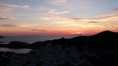 Güneş dramatik ve renkli bir şekilde batarken, Yunanistan 'daki Ios limanının panoramik manzarası