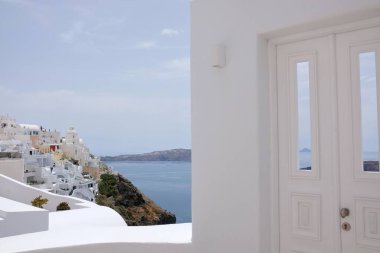 Güzel, beyaz bir kapı ve arka planda Santorini Yunanistan 'ın Fira köyü. 