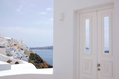 Güzel, beyaz bir kapı ve arka planda Santorini Yunanistan 'ın Fira köyü. 