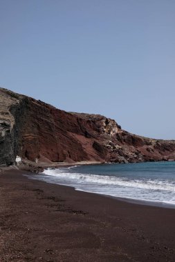 Santorini 'de rüzgarlı bir günde meşhur kızıl kumsalın panoramik manzarası 