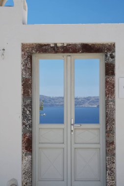 Santorini 'de tipik bir kapı Ege Denizi ve mavi gökyüzü manzarası nefes kesici.