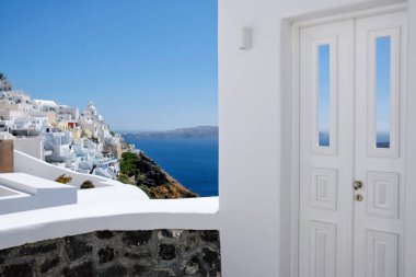 Tipik tasarım beyaz dekorasyon kapısı Santorini 'deki Fira ve Ege Denizi' nin nefes kesici manzaralı bir ara sokağın yanında.