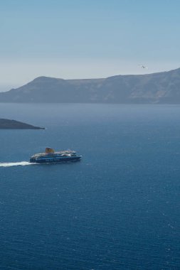 Santorini, Yunanistan - 10 Mayıs 2021 - Santorini 'deki Athinios limanından ayrılan bir feribot ve etrafta uçan martılar