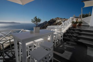 Fira Santorini 'de sandalyeleri ve masaları olan açık hava barından nefes kesici bir manzara.