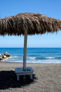 Perissa Santorini Yunanistan 'ın ünlü kumlu siyah plajında bir güneş şemsiyesi 