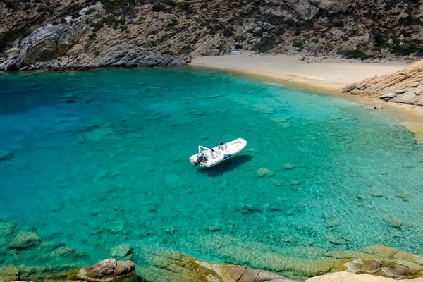 イオスのトリッピティの美しい砂浜とターコイズブルーのビーチで乾燥した木材 そして背景のボート — ストック写真