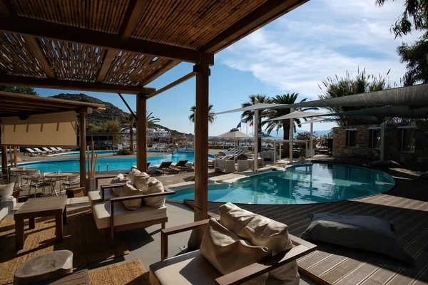 Ios, Yunanistan - 12 Haziran 2021: Yunanistan 'daki Mylopotas plajı önünde güneşli yataklı ve palmiye ağaçlı bir açık havuz manzarası