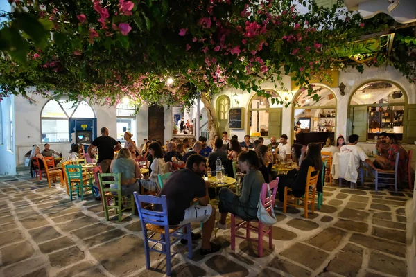 Ios, Yunanistan - 13 Haziran 2021: Turistler Ios köyündeki renkli bir açık hava barında içki içip canlı Yunan müziği dinliyorlar