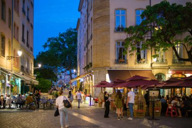 Lyon, Fransa - 10 Mayıs 2022: Açık hava restoranlarında yemek yiyen turistler ve geceleri eski Lyon kentinden geçen diğerleri.