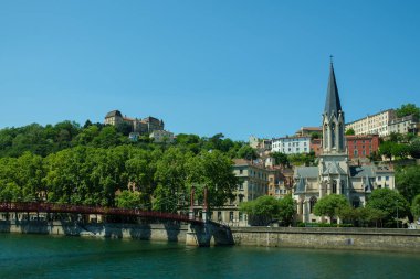 Lyon, Fransa - 11 Mayıs 2022: Kırmızı köprüyü geçen insanlar ve arka plandaki eski Lyon şehri