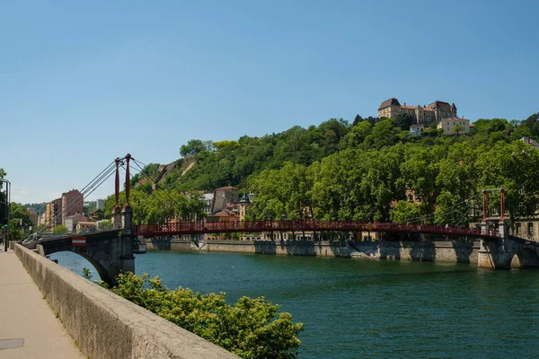 Lyon, Fransa - 11 Mayıs 2022: Kırmızı köprüyü geçen insanlar ve arka plandaki eski Lyon şehri