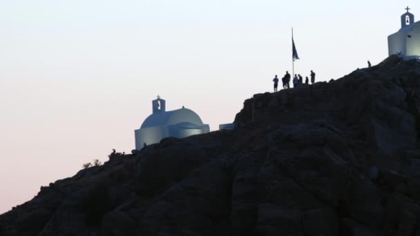 Toeristen Verkennen Pittoreske Kleine Kapelletjes Heuvel Ios Griekenland Terwijl Zon — Stockvideo