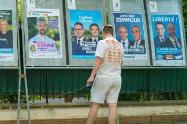 Paris, Fransa - 2 Haziran 2022: Paris 'teki kampanya posterlerinin çeşitli portrelerine bakan genç bir adam 