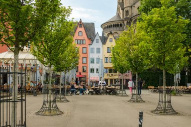 Köln, Almanya - 17 Mayıs 2022: Arka planda açık teras restoranında oturan insanları ve renkli geleneksel konut binalarını görmek