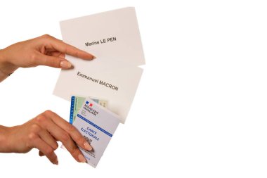Paris, Fransa - 26 Mayıs 2022: Fransız Deniz Piyadesi Le Pen ve Emmanuel Macron adayları için bir ulusal kimlik kartı, bir seçim kartı ve oy pusulası tutan bir kadın