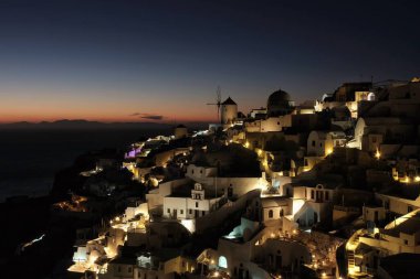 Nefes kesen Oia köyünün panoramik manzarası ve Santorini 'de inanılmaz bir günbatımı.