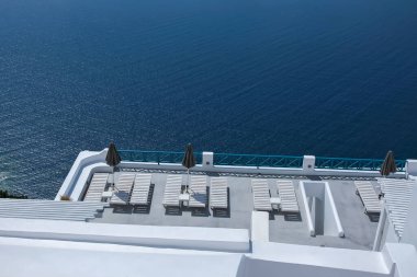 Güneşli yatakları ve Santorini Yunanistan 'daki Ege Denizi üzerinde nefes kesici manzarası olan güzel, bembeyaz bir teras.