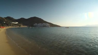 Ios, Yunanistan - 13 Eylül 2022: Güneşli yataklarda uzanan turistler Yunanistan 'daki güzel Mylopotas plajının keyfini çıkarıyorlar