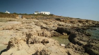 Yunanistan 'da küçük bir şapel, beyazlatılmış bir villa ve kayalık Magganari plajı manzarası