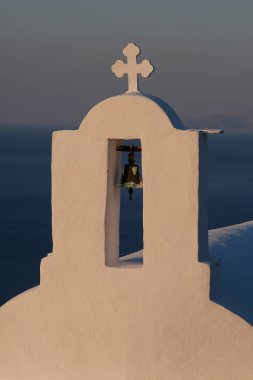 Güneş arka planda batarken, Yunanistan 'daki bir ortodoks kilisesinin tepesinde bir haç ve çan.