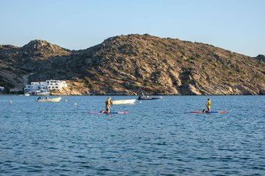 Ios, Yunanistan - 11 Eylül 2022: Genç turist Mylopotas 'ın ünlü plajında ayakta kürek çekiyor