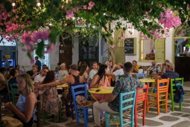 Ios, Yunanistan - 11 Eylül 2022: Ios siklades Yunanistan 'da renkli sandalyeler ve yerel halk canlı geleneksel müzik eşliğinde açık hava manzaralı teras