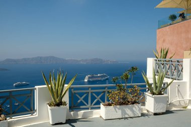 Fira, Santorini - 4 Eylül 2022: Fira Santorini 'de çiçek saksılarıyla süslenmiş bir çatıdan panoramik yolcu gemileri manzarası
