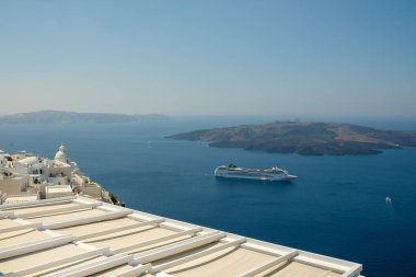 Fira, Santorini - 4 Eylül 2022: Kalderanın yanındaki yolcu gemisinin panoramik manzarası, ve arka planda güzel mavi bir gökyüzü