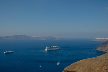 Fira, Santorini - 4 Eylül 2022: Kalderanın yanındaki iki yolcu gemisinin panoramik manzarası ve Santorini 'nin arka planında güzel mavi bir gökyüzü
