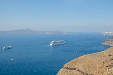 Fira, Santorini - 4 Eylül 2022: Kalderanın yanındaki yolcu gemisinin panoramik manzarası, ve arka planda güzel mavi bir gökyüzü