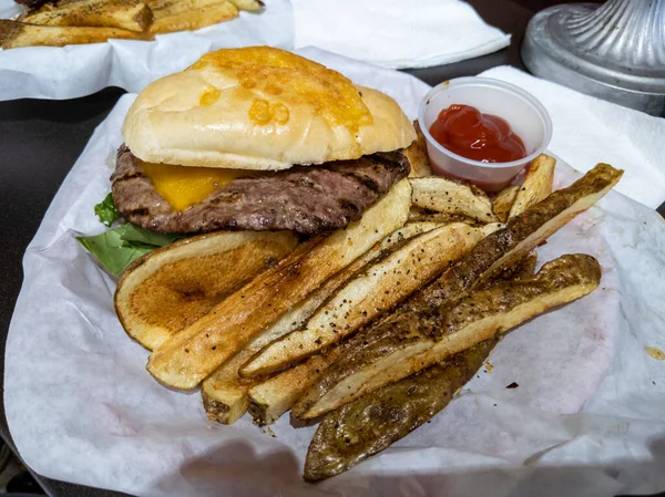 地元のバーガーダイブでバスケットで提供される脂っこいチーズバーガーとシャキッとしたステーキフライの眺めを見下ろします — ストック写真