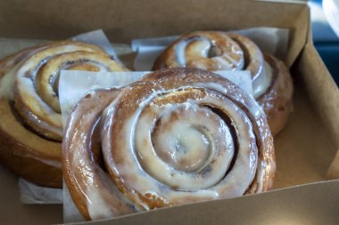 Geniş, ev yapımı tarçınlı rulolarla dolu açık bir pasta kutusunun açılı görüntüsü