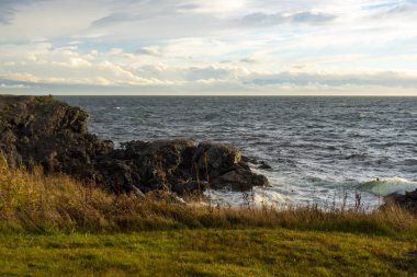 Beyaz, köpüklü dalgalar San Juan Adası, WA 'da gün batımında kıyı kayalarına çarpıyor.