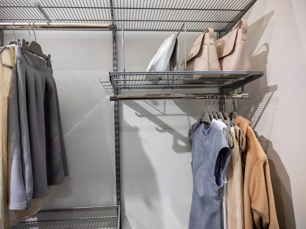 View of a large, walk in closet with metal organizing racks, storing dresses, skirts, jackets, and purses inside of it