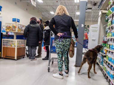 Woodinville, WA USA - Şubat 2022: Birkaç kişi ve köpeği ile birlikte Petsmart mağazasının kasasında bekleyen bir kadın