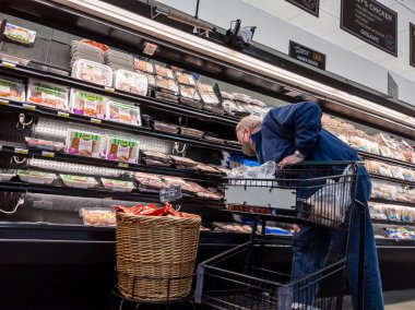 Woodinville, WA USA - Ocak 2022: Bir Haggen marketinin et reyonundan alışveriş yapan yaşlı bir adamın manzarası.